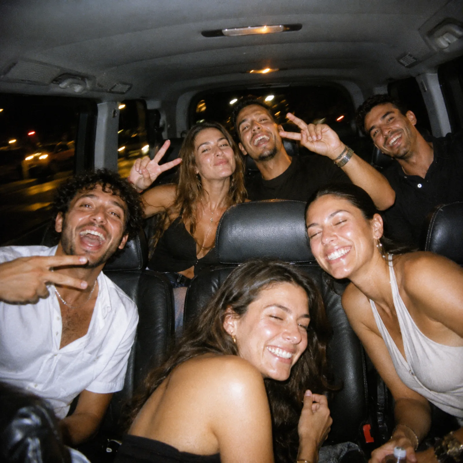 Six amis hilares entassés à l'arrière du van SDM la nuit, photo flash argentique
