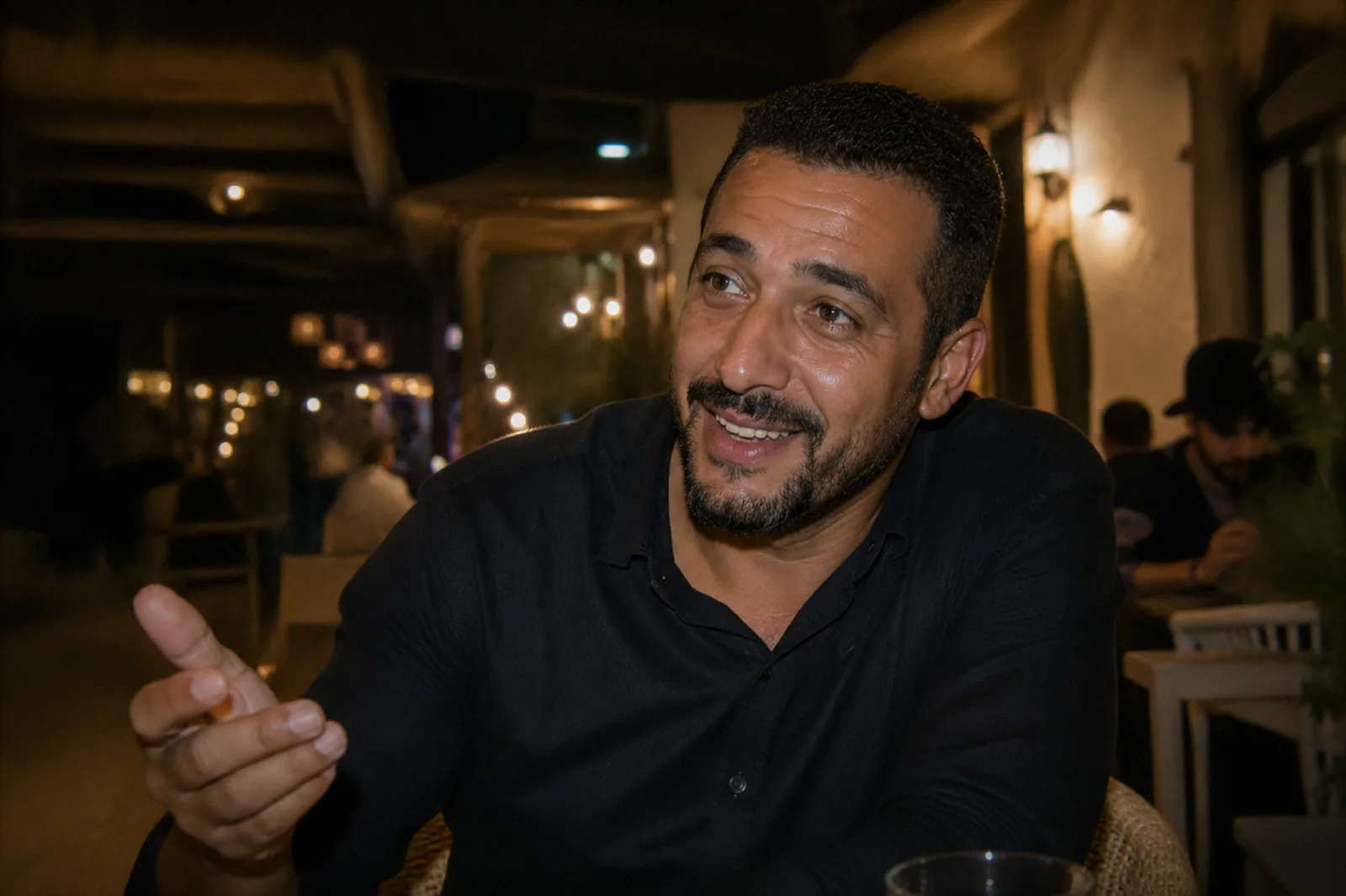 Karim, chauffeur SDM, attablé à une terrasse de café la nuit, en pleine conversation chaleureuse